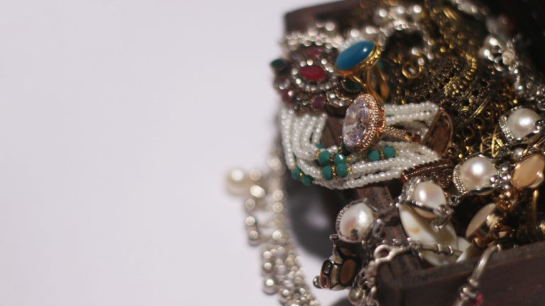 Erilaisia koruja tummassa puulaatikossa vaalealla taustalla